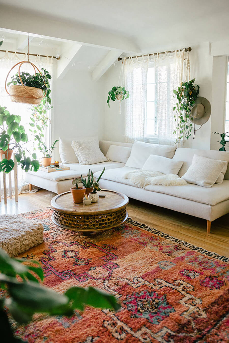 un living moderno con textiles de materiales naturales, una mesa de centro circular, muebles de tonos neutros y plantas