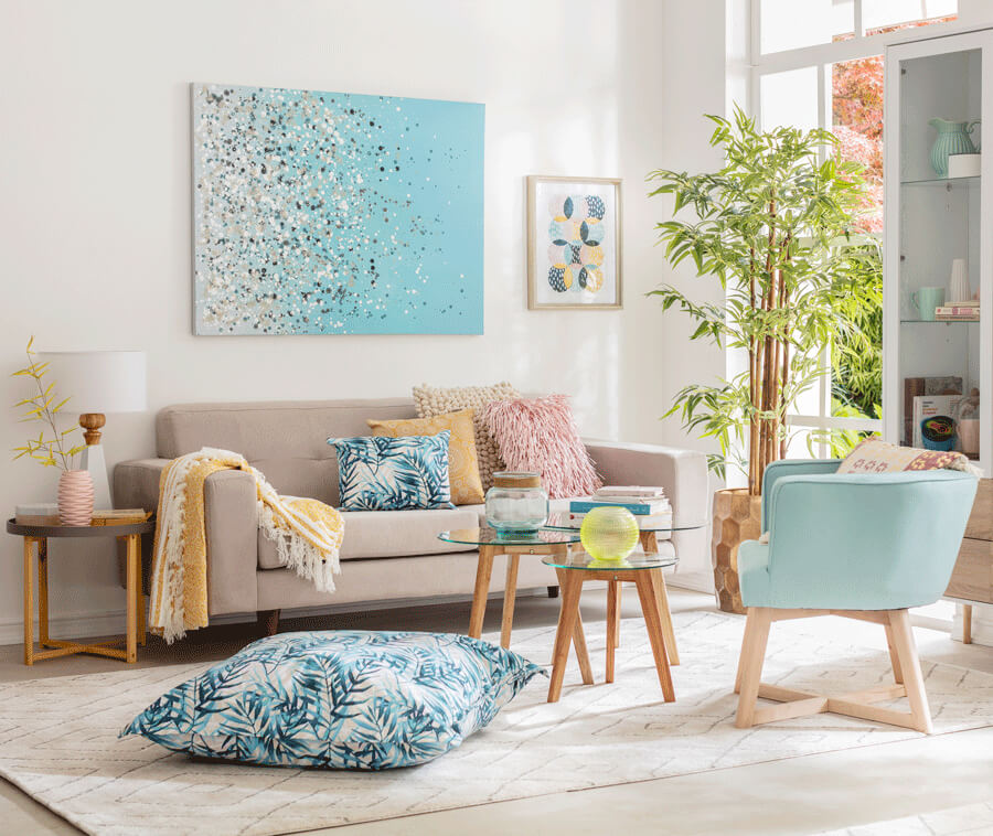 Un living con colores neutros y celestes, con un sofá pegado a la pared como parte de la decoración de living