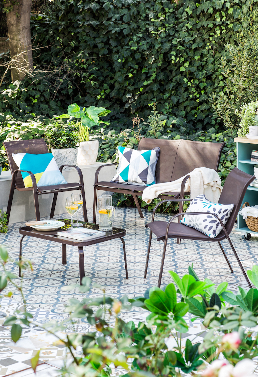 Quincho con una terraza metálica negra, con un sillón, dos sitiales y una mesa de centro. Cojines geométricos de color blanco, gris, celeste y amarillo.