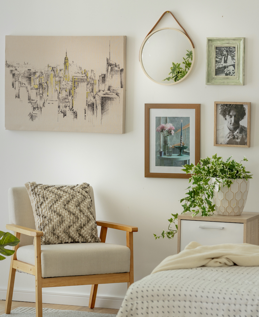 Rincón de una sala de estar con una poltrona de madera y una composición de cuadros deco detrás de ella.