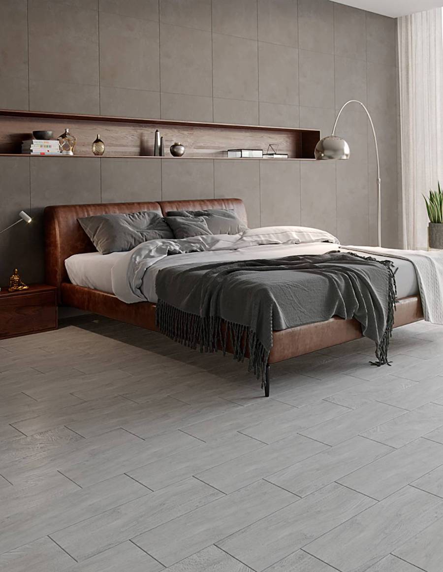 Dormitorio con piso de cerámica imitación madera gris. Hay una cama de estructura de cuero y ropa de cama en tonos grises.