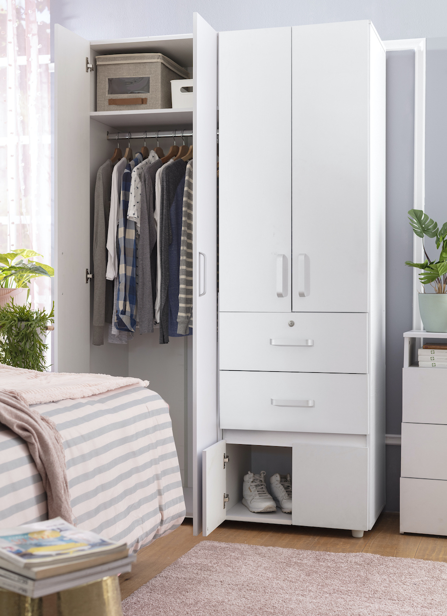 Dormitorio con gran closet blanco con puertas y cajones. Dentro se ven unas camisas colgadas y un par de zapatos.