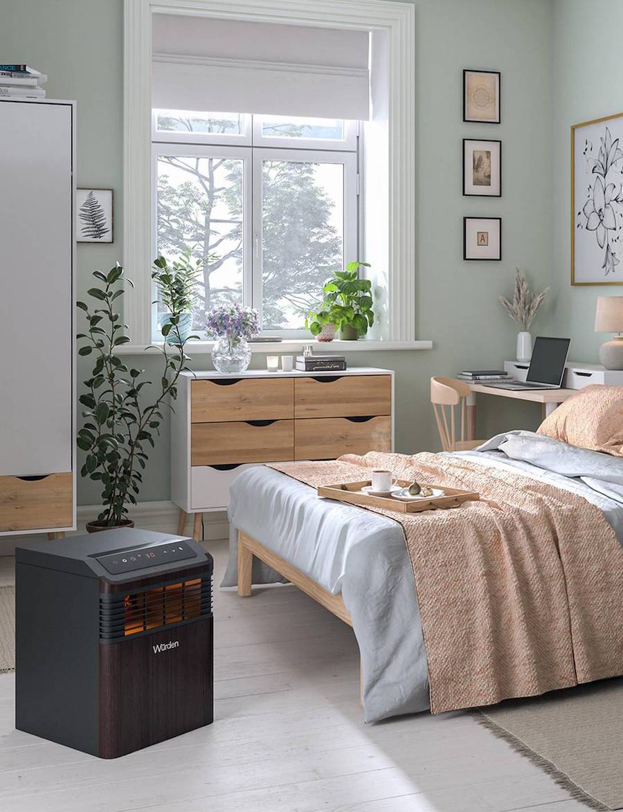Calefactor infrarrojo, de olor negro y estilo moderno, disponible en Sodimac. Está ubicado en un dormitorio nórdico, junto a una cama con plumón gris y manta color salmón