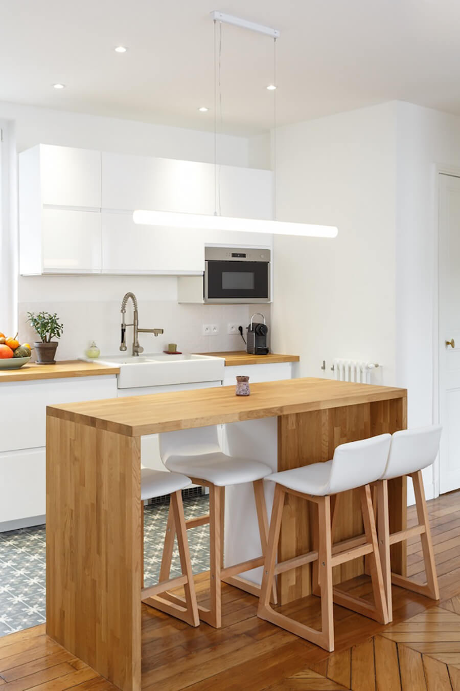 Una cocina abierta o una cocina integrada moderna con una mesa central de madera y pisos altos blancos con patas de madera