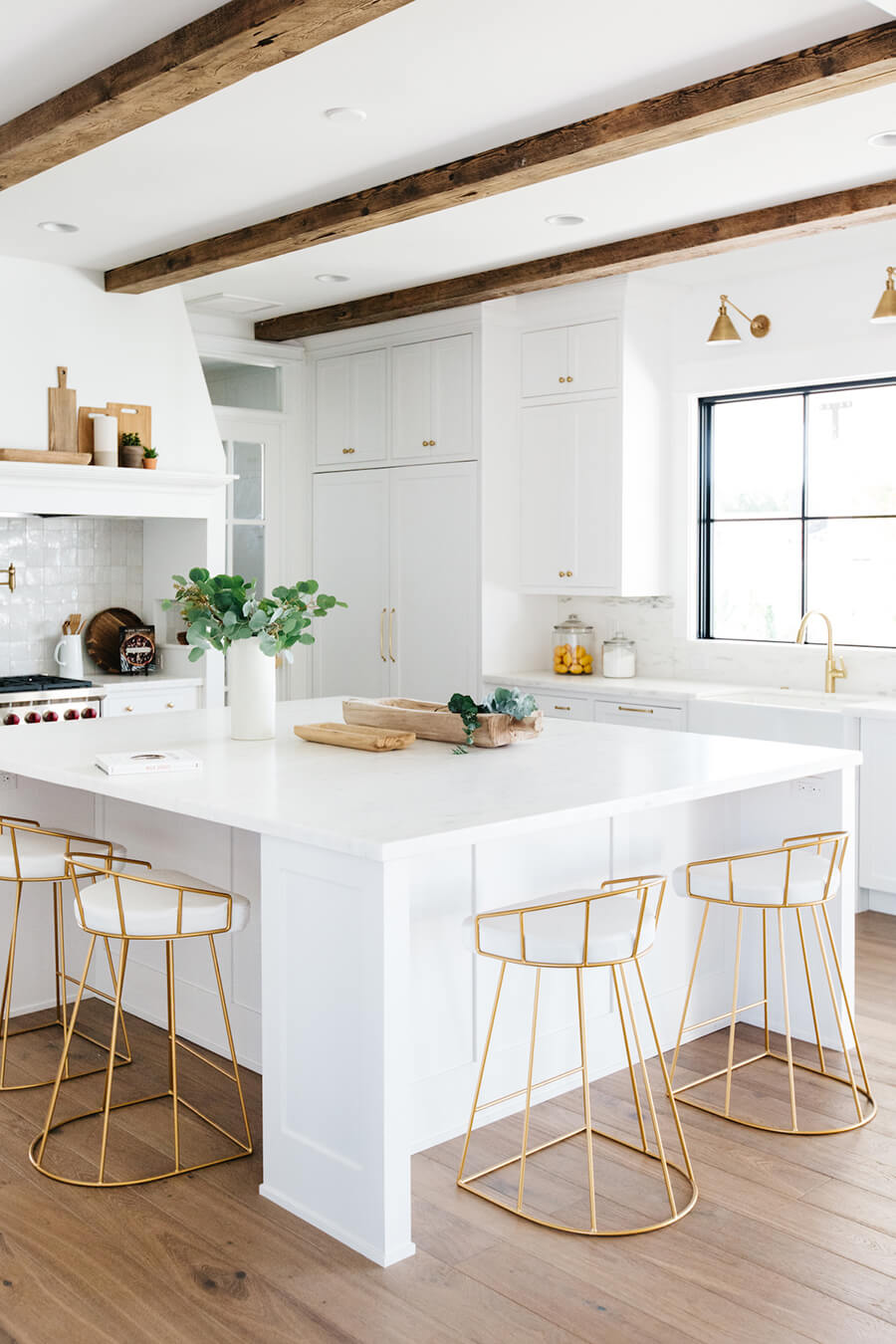 Una cocina integrada moderna con muebles blancos y pisos de estructura dorada