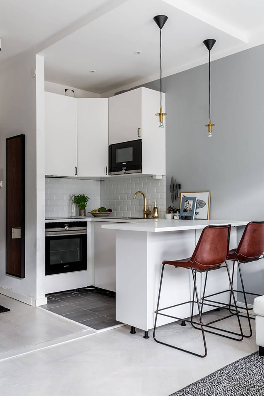 Una cocina integrada moderna de color blanco con un mesón blanco y asientos altos