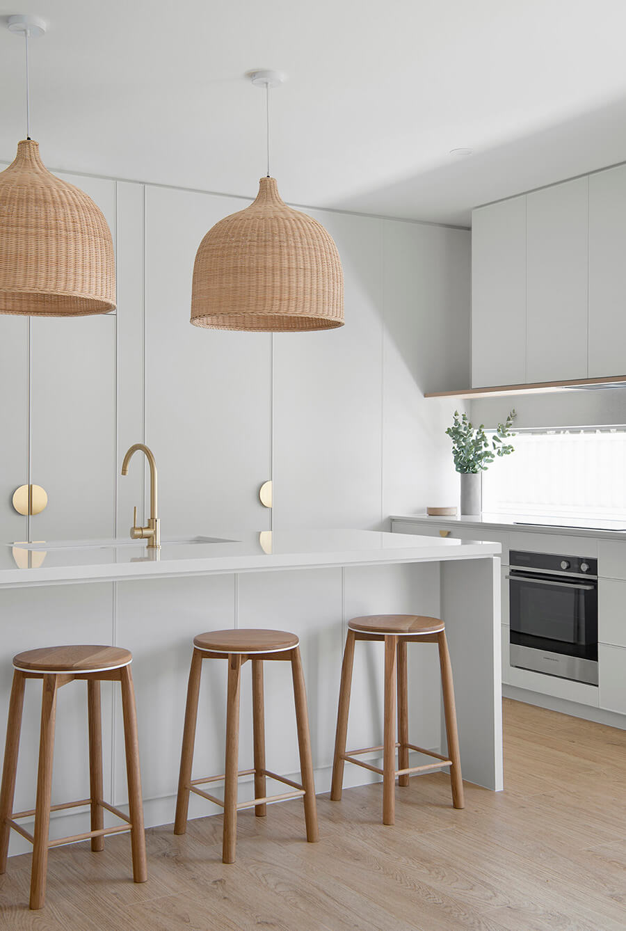 Esta imagen muestra una idea para cocina con muebles estéticamente sencillos, como una isla de cocina blanca y pisos de madera altos.