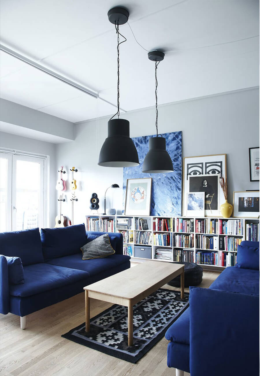 Un living con un librero grande y 2 sofás de color azul enfrentados para mejorar la decoración de living
