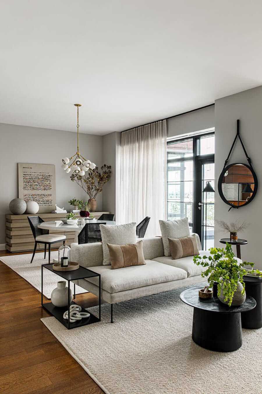 Un living comedor con contraste entre colores claros y negros, con un sofá puesto como separador de ambientes