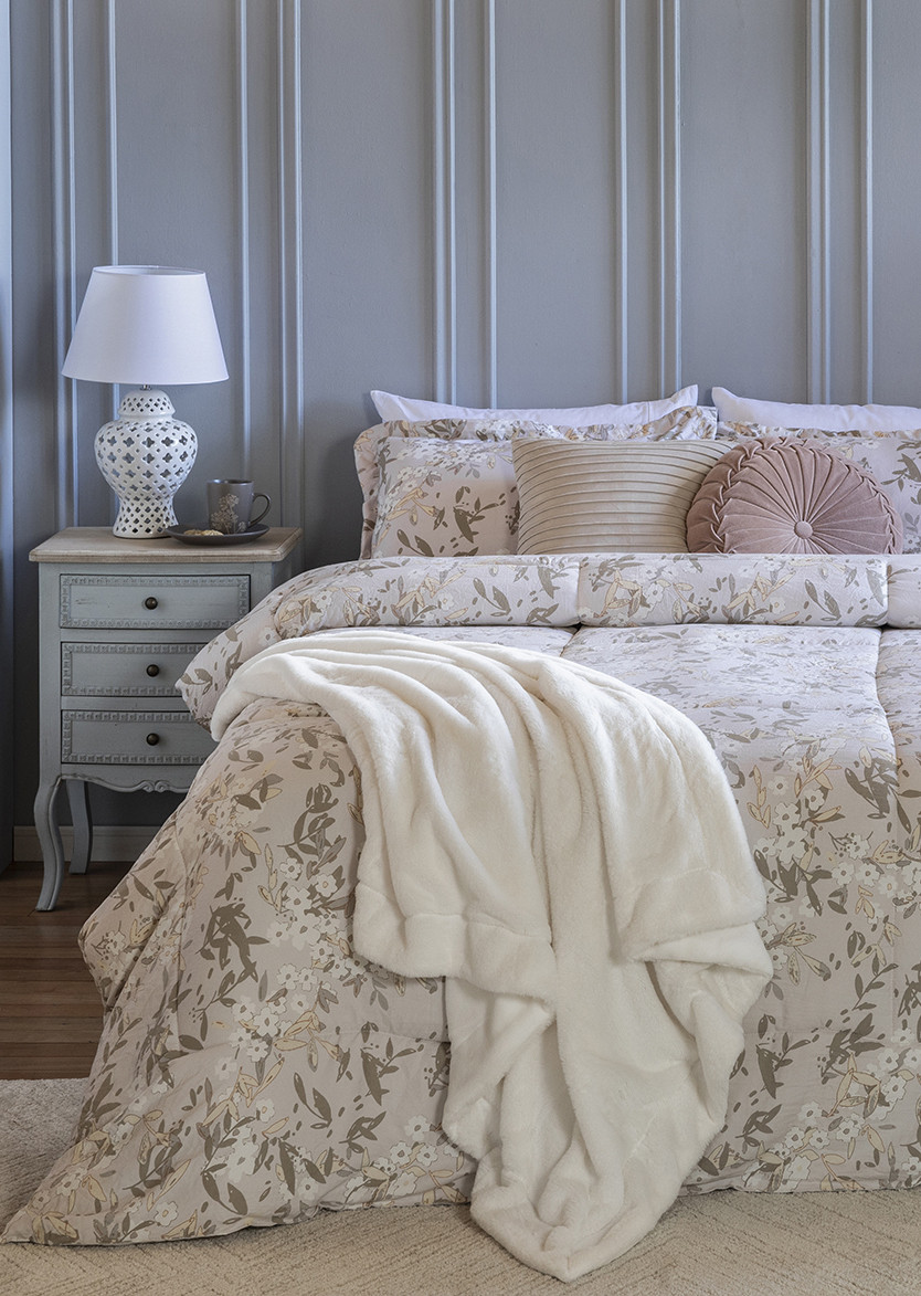 Dormitorio de estilo clásico con una pared gris con molduras, cama con un plumón beige de flores y una manta blanca sobre él. 