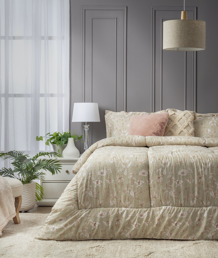 Dormitorio estilo coquette, con cama de dos plazas con plumón beige oscuro con diseño floral. Cojines beige y rosa claro. Muro gris con molduras y gran ventana con visillo blanco