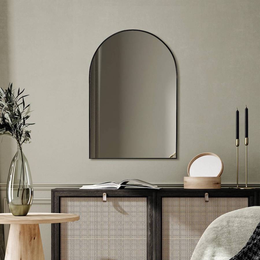 Living de estilo lujo silencioso con un espejo con marco negro en el muro, sobre un buffet negro con puertas de ratán. 