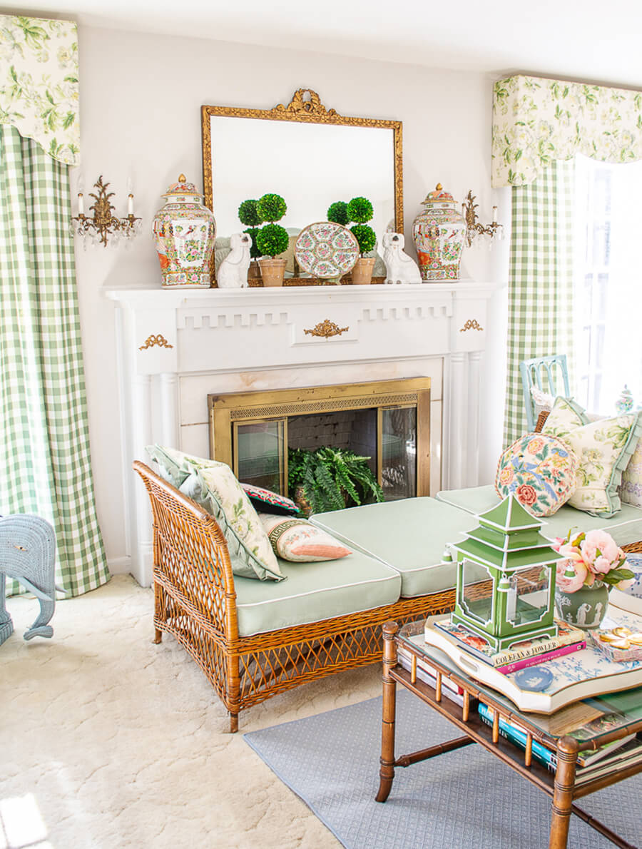 Decoración ecléctica de living con chimenea con tonos verde menta y muebles de madera y mimbre, con elementos de chic vintage y detalles dorados