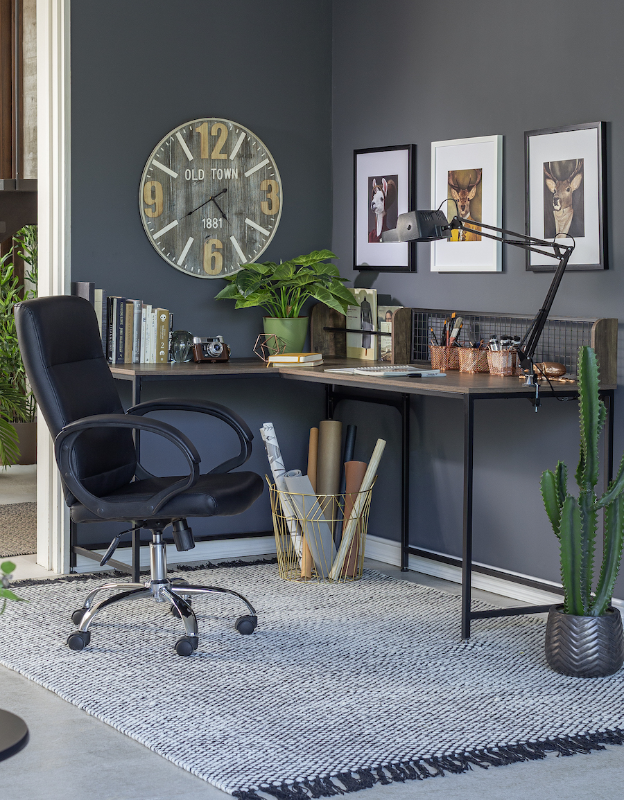 Escritorio de estilo ejecutivo urbano con una silla negra con ruedas. Sobre el escritorio hay una lámpara de mesa, lapiceros de cobre, una planta, libros y otros artículos de escritorio, todos ordenados y organizados. 
