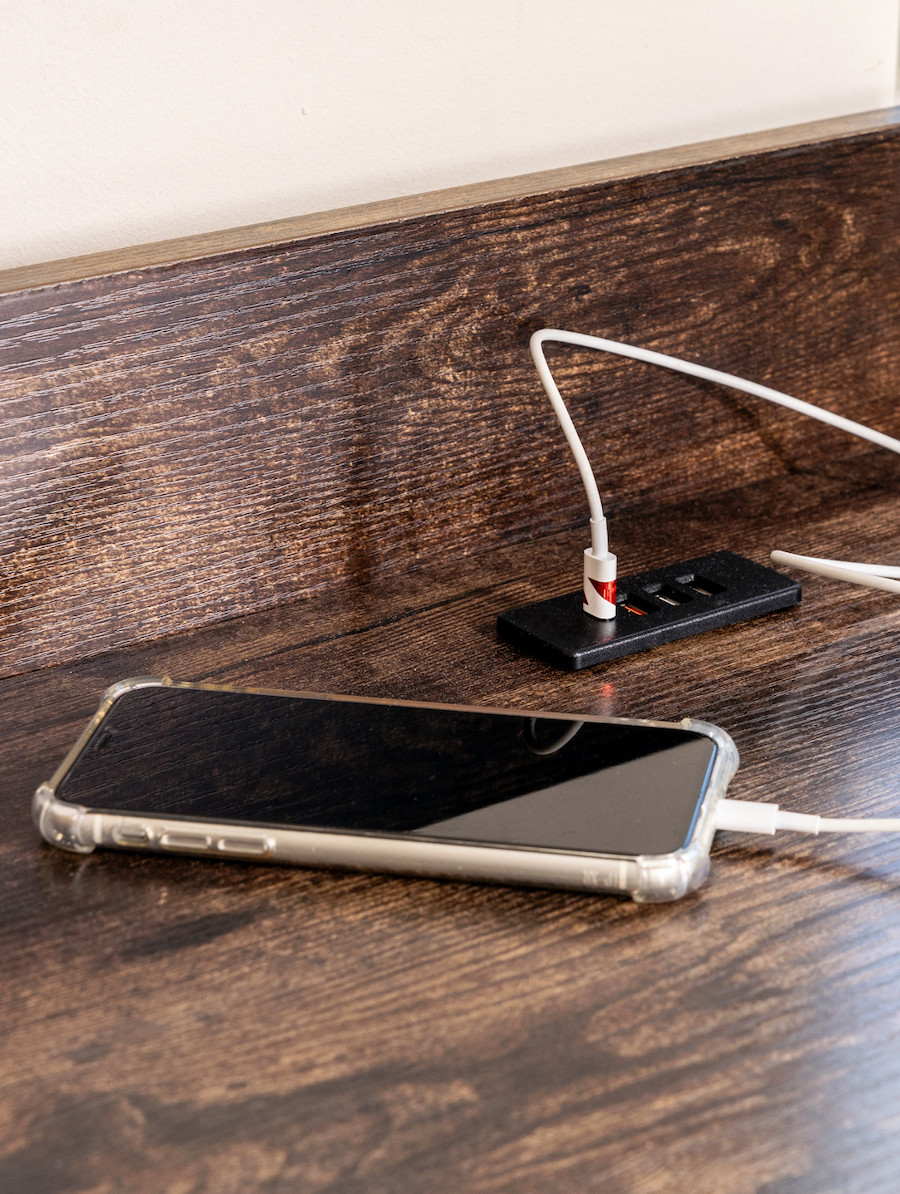 Detalle de un celular conectado a la corriente sobre un escritorio de madera oscura