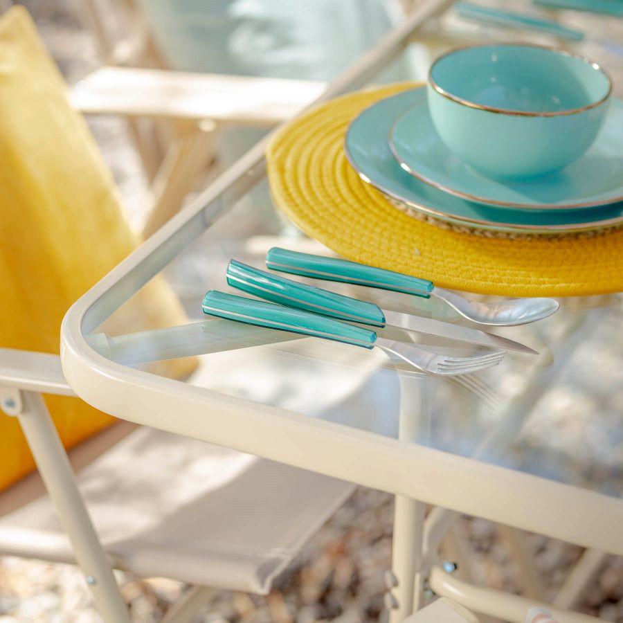 Detalle de una mesa de comedor de terraza con un individual redondo amarillo, y platos y bowl color celeste. 