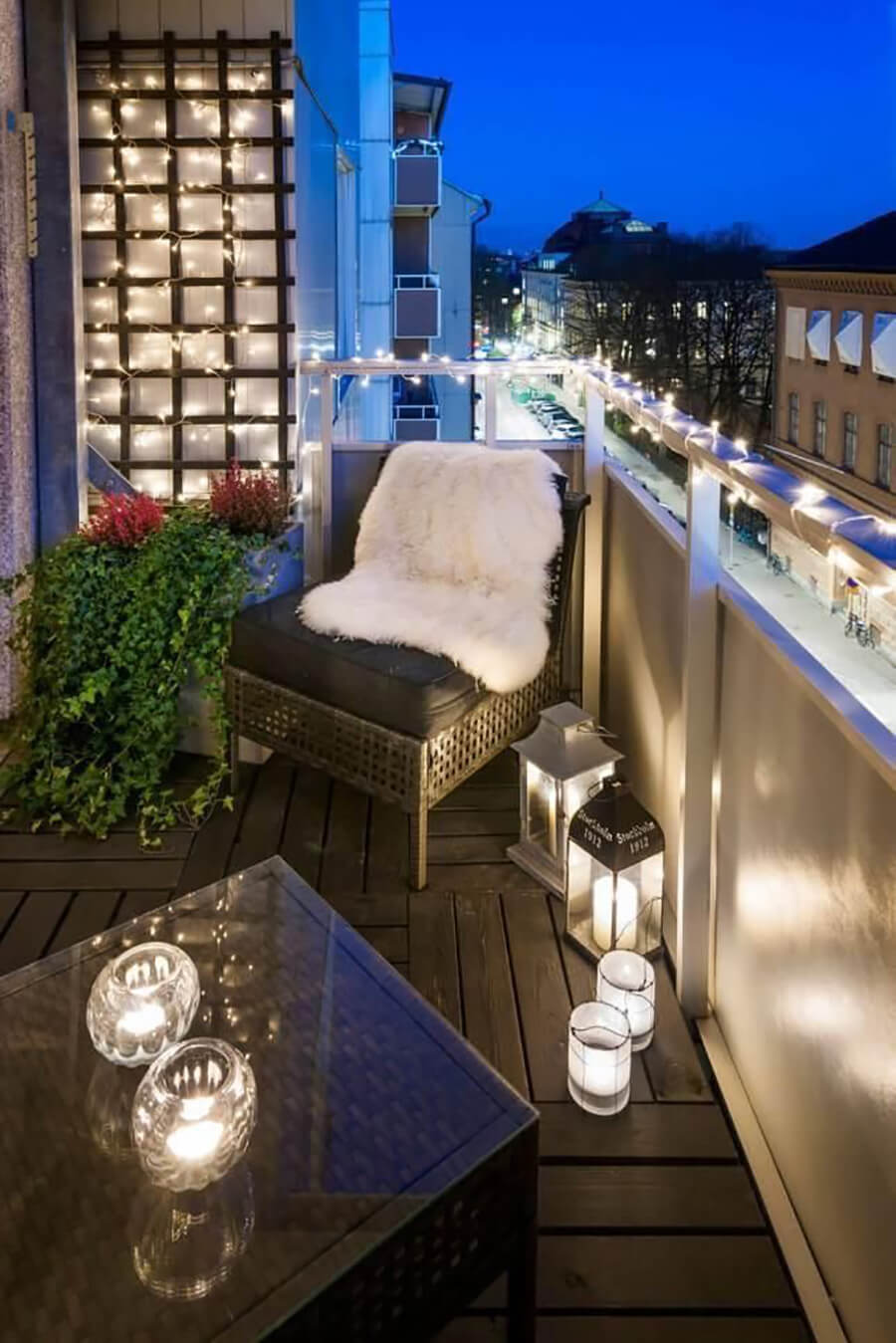 Un balcón urbano con tiras de luces led y fanales. Completan la iluminación velas sobre la mesa y en el piso.