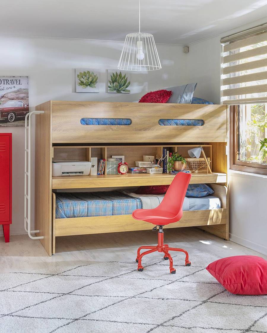 Dormitorio infantil en tonos grises con detalles en rojo. Hay un camarote de madera con espacio para guardar y un escritorio incorporado. Frente a él hay una silla de escritorio roja.